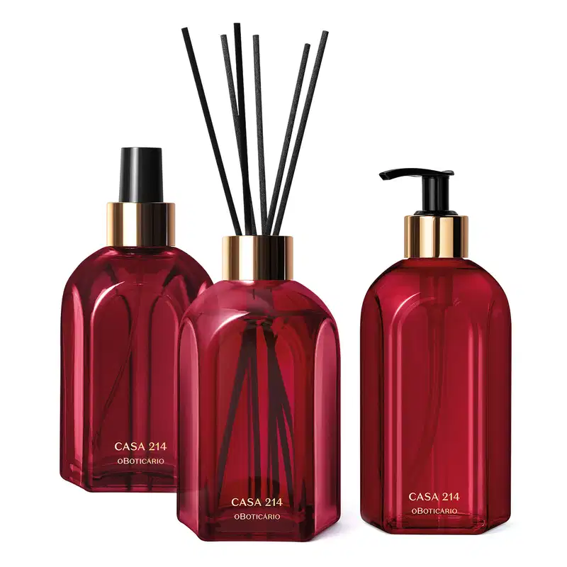 Três vidros vermelhos da marca Casa 214 Gardênia Imperial: um difusor de ambientes com varetas, um sabonete líquido com bico dosador preto e um aromatizador de ambientes com válvula spray preta.