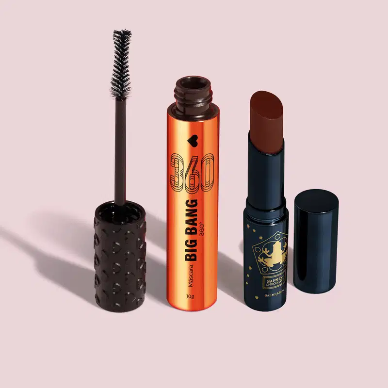 Máscara de cílios Big Bang 360 em embalagem laranja metalizada com tampa e aplicador na cor preta, acompanhada de um balm labial na cor marrom em embalagem preta com detalhe dourado, ambos da marca Quem Disse, Berenice? em fundo cinza claro.