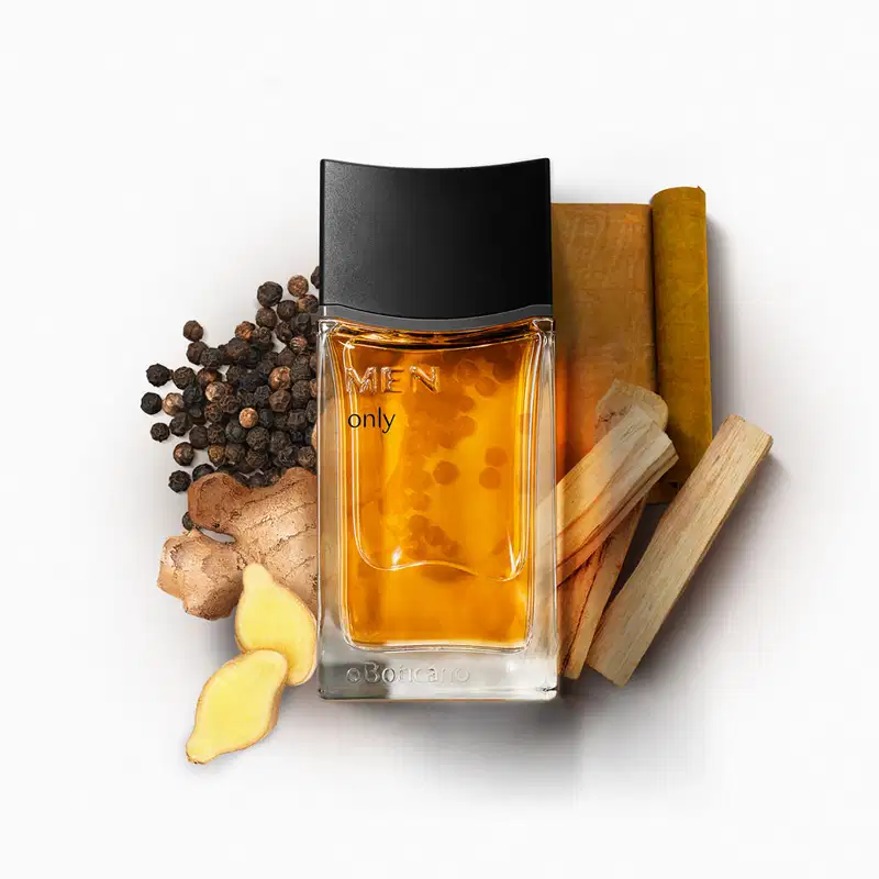 Imagem de um frasco de desodorante colônia da marca Men Only sobre superfície branca, rodeado por especiarias, raízes e pedaços de madeira, em cenário minimalista com cores quentes.