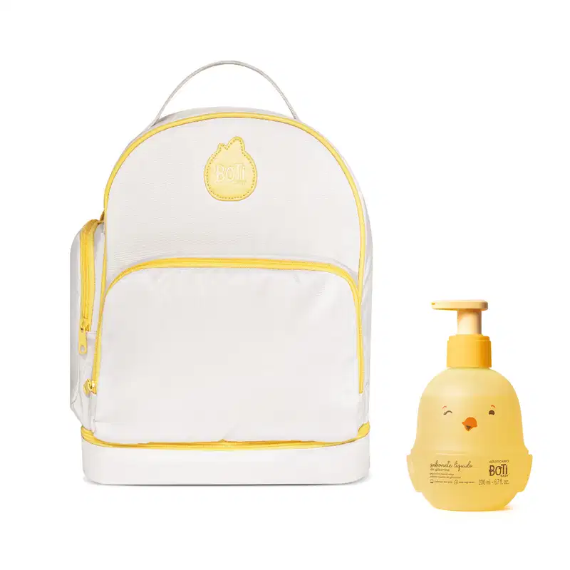 Mochila branca com detalhes amarelos da marca Boti Baby, com bolso frontal e alça de transporte. Acompanhada de um item de corpo e banho com embalagem em formato de pintinho amarelo com válvula pump.
