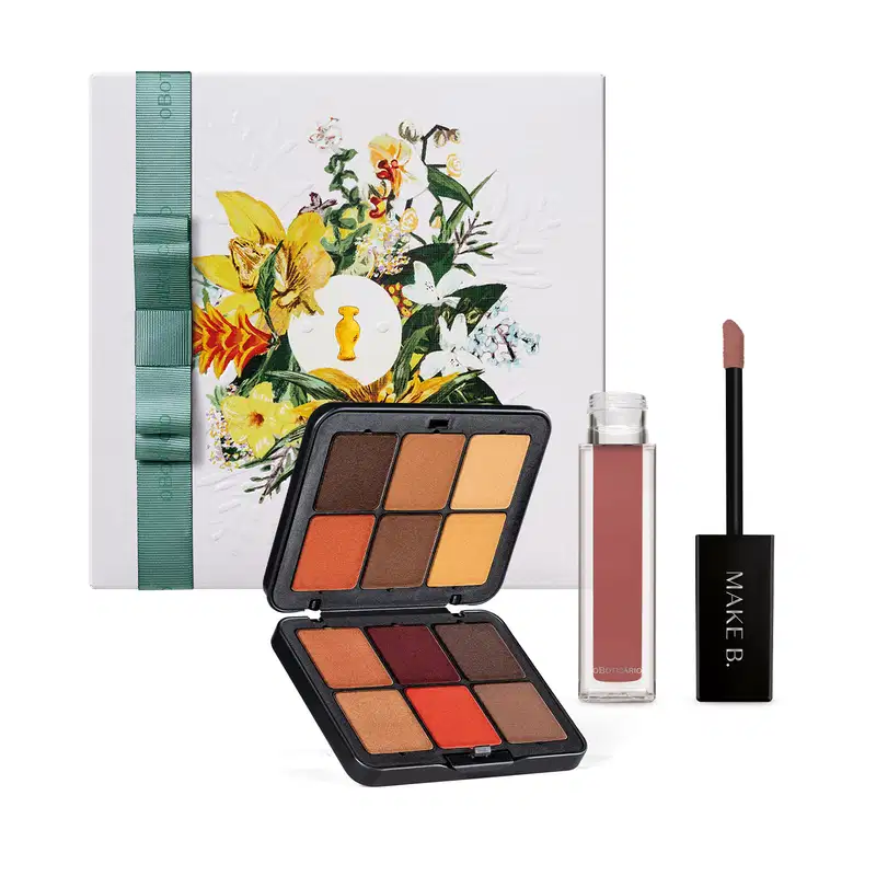 Kit contendo caixa com ilustração de flores, paleta multifuncional com nove tons terrosos e quentes em embalagem preta, com espelho, acompanhada de batom líquido em tom rosado com frasco transparente e tampa preta, todos da marca Make B.