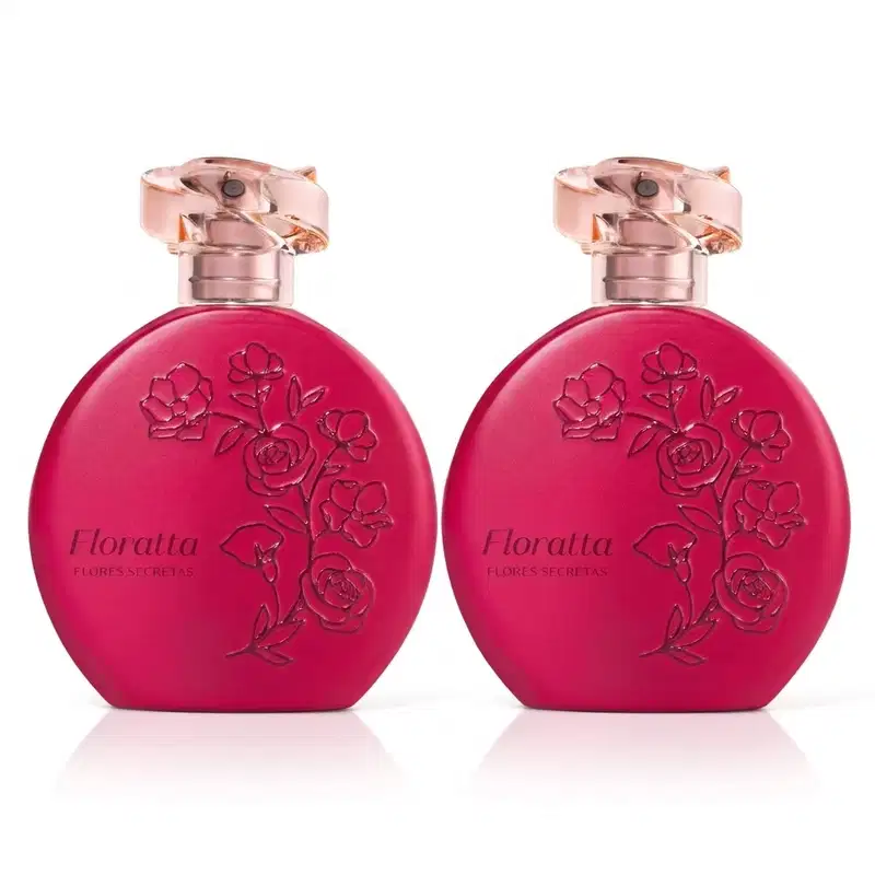 Dois frascos de item de perfumaria da marca Floratta Flores Secretas em formato redondo, cor rosa vibrante opaco com detalhes em relevo com flores estilizadas e tampa em acrílico rosado transparente e borrifador dourado posicionados lado a lado.