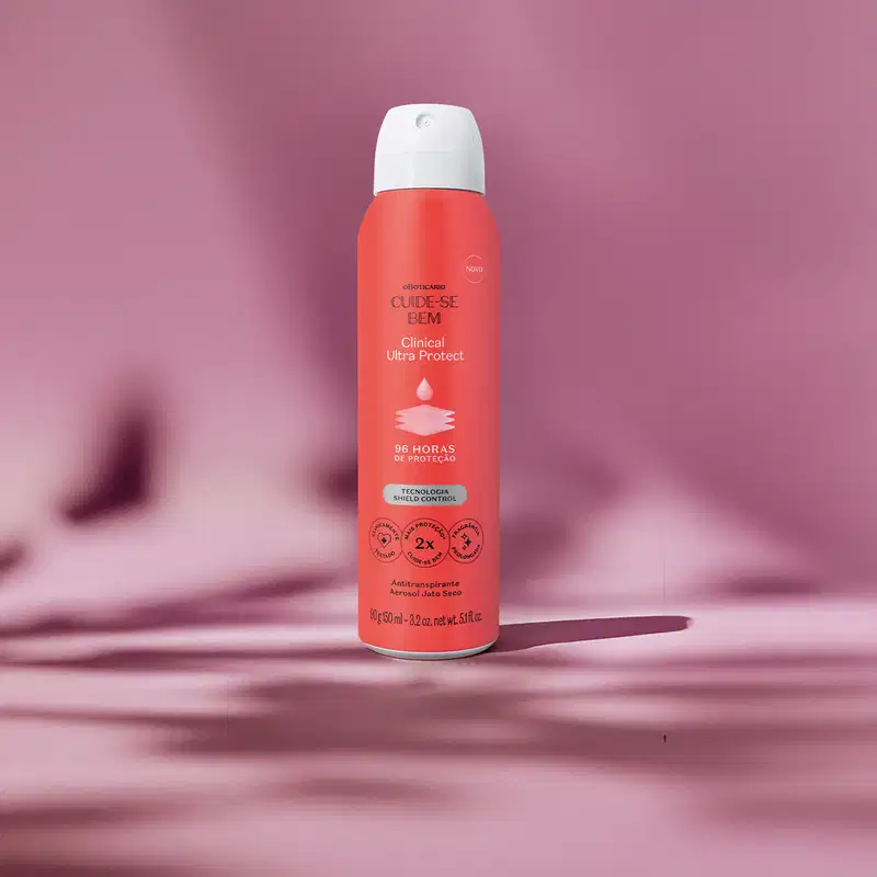 Frasco laranja com tampa spray branca, detalhe azul e letras pretas e brancas contendo 90g/150ml de desodorante antitranspirante aerossol da marca Cuide-se Bem Clinical Protect em um fundo lilás com sombras.