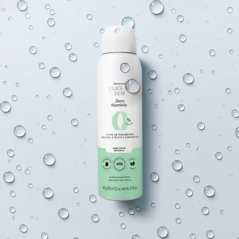 Frasco spray branco com detalhe azul e letras pretas contendo 90g/150ml de antitranspirante aerossol jato seco da marca Cuide-se Bem Zero Alumínio em fundo azul repleto de gotas de água, inclusive sobre a embalagem.