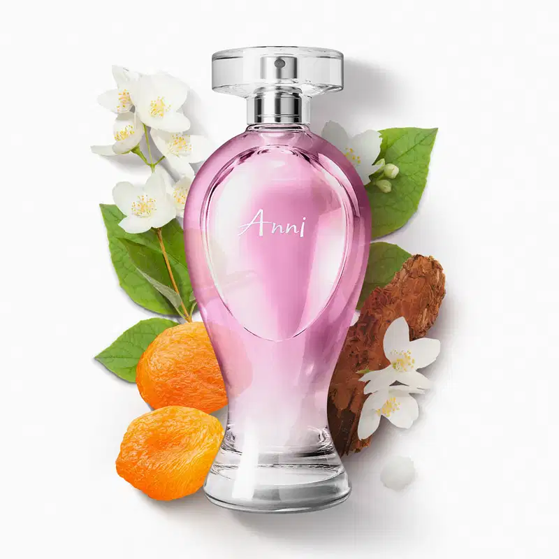 Vidro transparente em formato curvilíneo com líquido rosa, pulverizador prateado e tampa transparente contendo desodorante colônia Boticollection Anni cercado por flores brancas, folhas verdes, madeira e damascos.