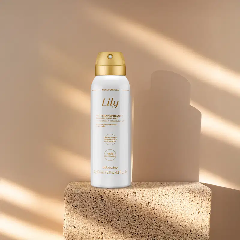 Um frasco branco com tampa e letras douradas de desodorante antitranspirante aerossol da marca Lily está em cima de uma pedra simulando mármore e em fundo rosa com muitas sombras.