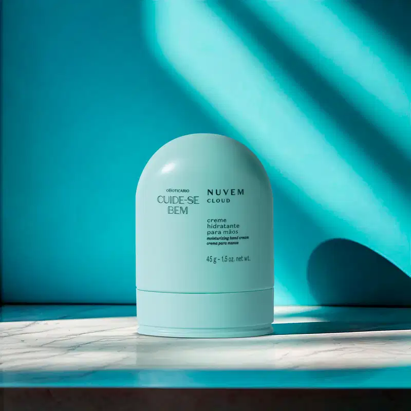 Embalagem azul de creme hidratante para as mãos Cuide-se Bem Nuvem em um cenário escuro em tons de azul com algumas luzes naturais.