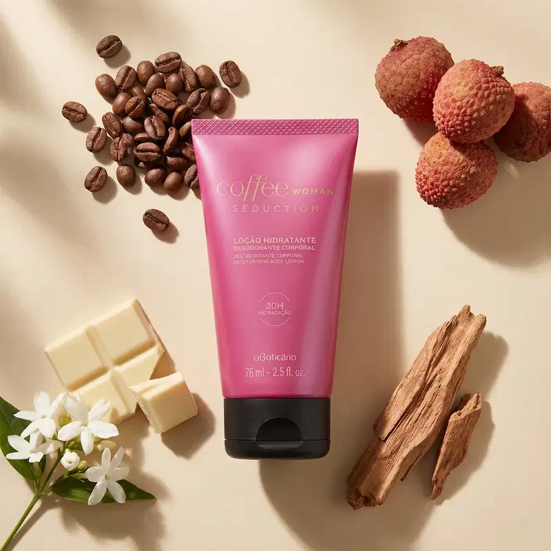 Recipiente rosa de loção hidratante corporal da marca Coffee Woman Seduction, cercado por grãos de café, flores brancas, pedaços de chocolate branco e pedaços de madeira. O cenário sugere um ambiente de cuidados pessoais e relaxamento.
