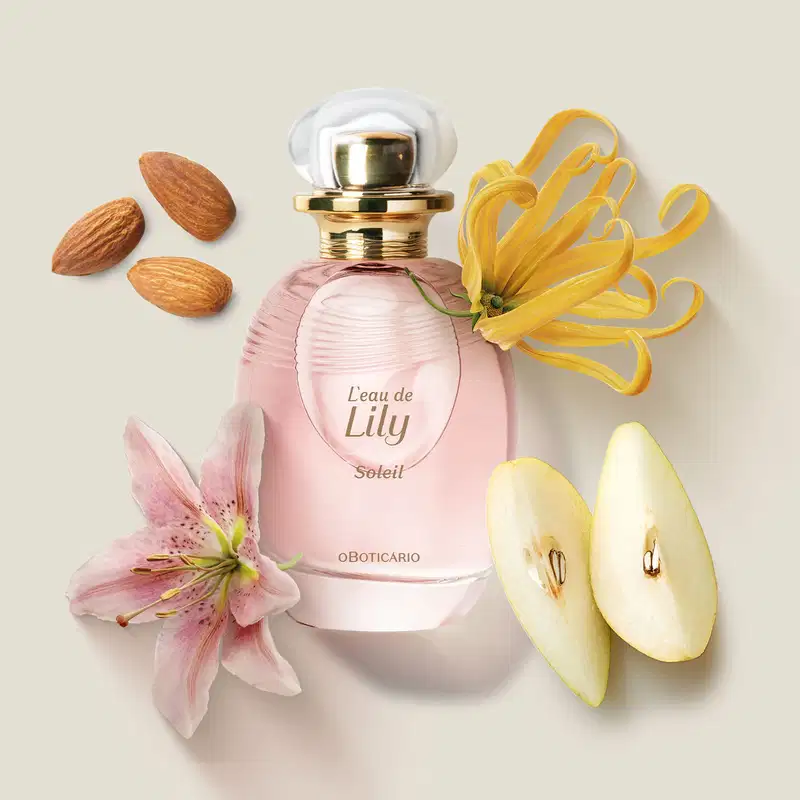Vidro transparente oval com líquido rosa, borrifador dourado e tampa transparente contendo desodorante colônia L'eau de Lily Soleil    com amêndoas, flores e pera ao redor.