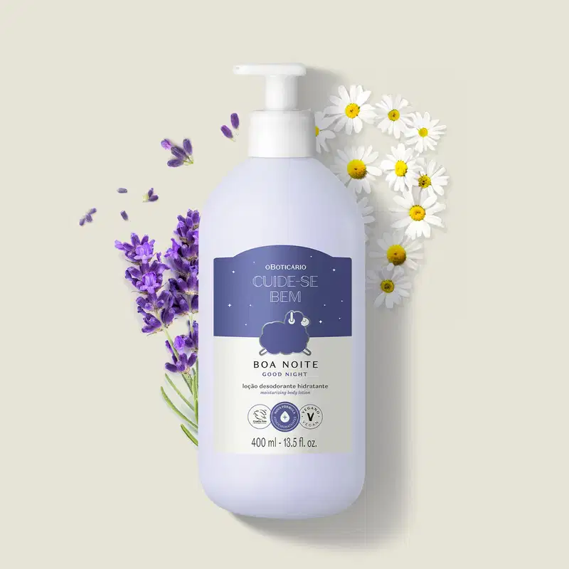Frasco branco com bomba dosadora e rótulo azul escuro e branco com ovelhinha ilustrada contendo 400ml de loção hidratante corporal Cuide-se Bem Boa Noite cercado por flores de lavanda e margaridas brancas em fundo bege claro.