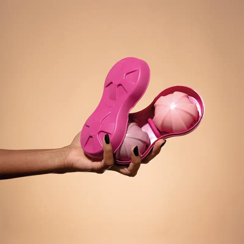 Mão segurando uma base para sólidos na cor rosa da marca Nativa SPA, ideal para produtos em barra. Dentro deles, dois itens como sabonete ou shampoo em barra. O fundo é em tons de rosa.