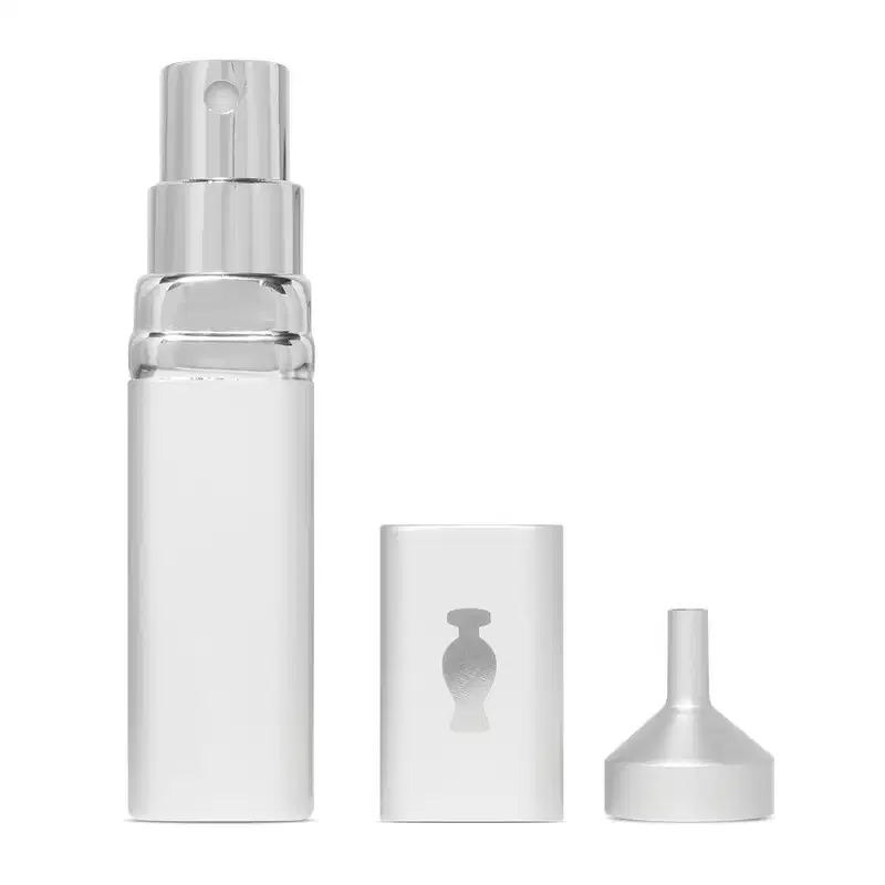 Porta-perfume com vaporizador em tubo prateado com o logo da marca O Boticário em cinza na parte superior. Ao lado, um mini funil.