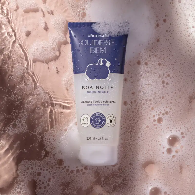 Bisnaga azul e lilás com tampa branca e desenho de ovelhinha ilustrado no rótulo contendo 200ml de sabonete líquido esfoliante Cuide-se Bem Boa Noite em meio a muita espuma branca e fundo rosa.