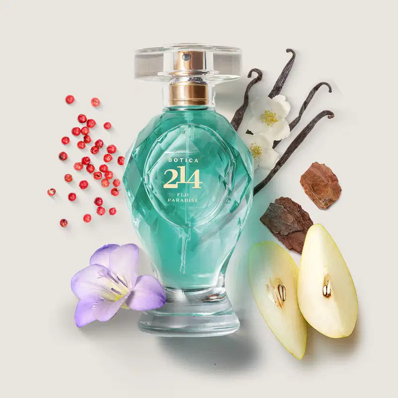 Vidro transparente lapidado com líquido azul, borrifador dourado, tampa transparente e letras douradas de Eau de Parfum Floral Especiado da marca Botica 214 Fiji Paradise com peras frescas, flor de frésia, vagens de baunilha e pimenta rosa ao redor.