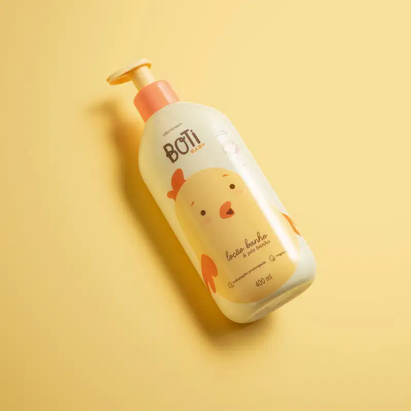 Frasco amarelo claro com ilustração de um passarinho amarelo com detalhes, tampa e bomba dosadora laranjas contendo 400ml de loção hidratante banho e pós banho da marca Boti Baby em fundo alaranjado.