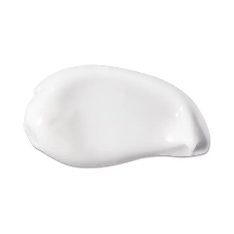 Textura branca e cremosa da loção hidratante corporal da marca Boti Baby com aparência brilhante e fluída espalhada em superfície branca.
