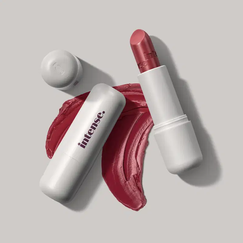 Batom cremoso na cor vermelho 350 da marca Intense, em embalagem toda branca com letras pretas na tampa, com uma quantidade de produto espalhada no fundo cinza.