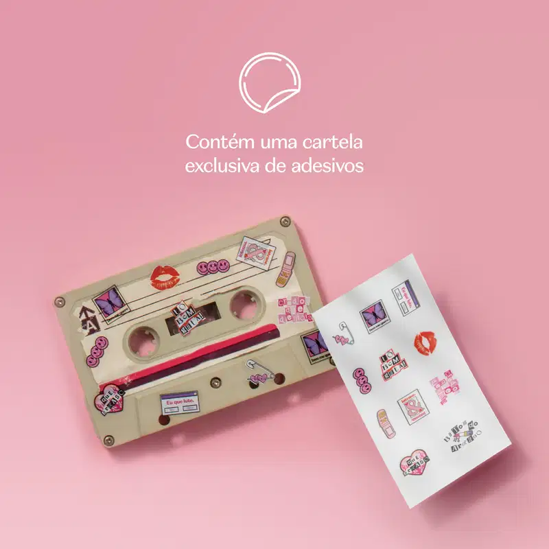 Fita K7 em tons de bege com vários adesivos, ao lado de uma cartea de adesivos em fundo rosa.