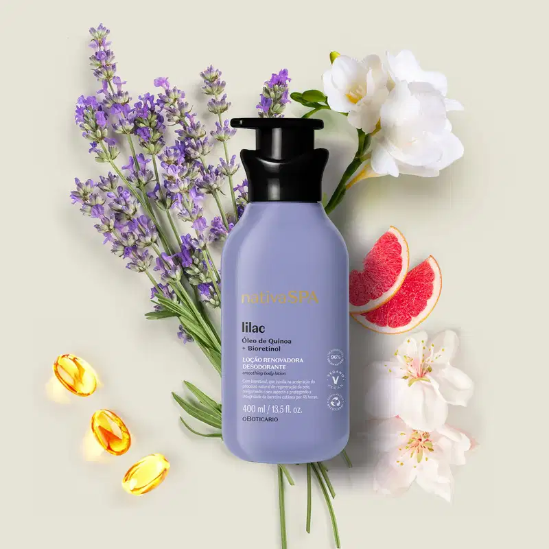 Frasco lilás com bomba dosadora preta e letras douradas, brancas e pretas de loção renovadora hidratante corporal da marca Nativa SPA Lilac em meio a flores de lavanda, pétalas de flores brancas e fatias de toranja vermelha sobre fundo bege claro.