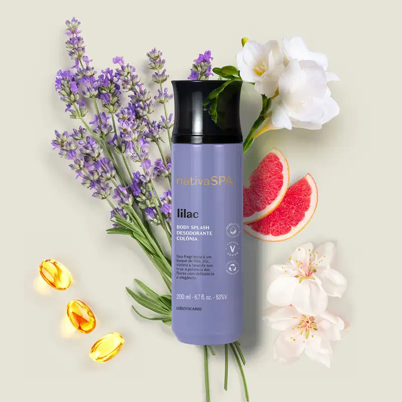 Buquê de lavanda, flores brancas e fatias de toranja em superfície clara, com um frasco cilíndrico na cor lilás com tampa preta e letras brancas e pretas  de body splash Nativa SPA Lilac.