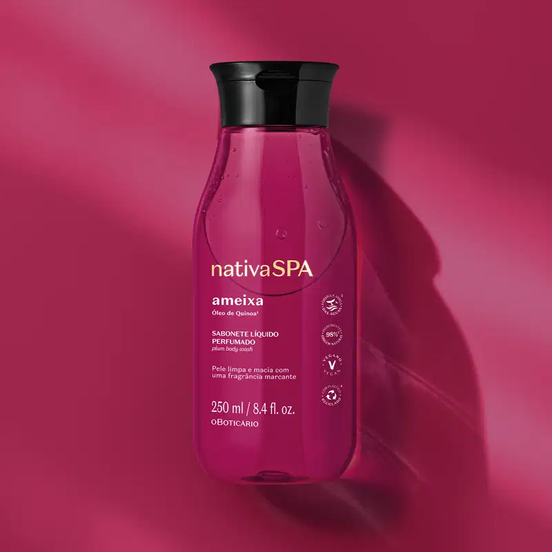 Frasco na cor rosa vibrante com tampa preta e rótulo com letras douradas e brancas contendo sabonete líquido perfumado Nativa SPA Ameixa em fundo em tons de rosa.