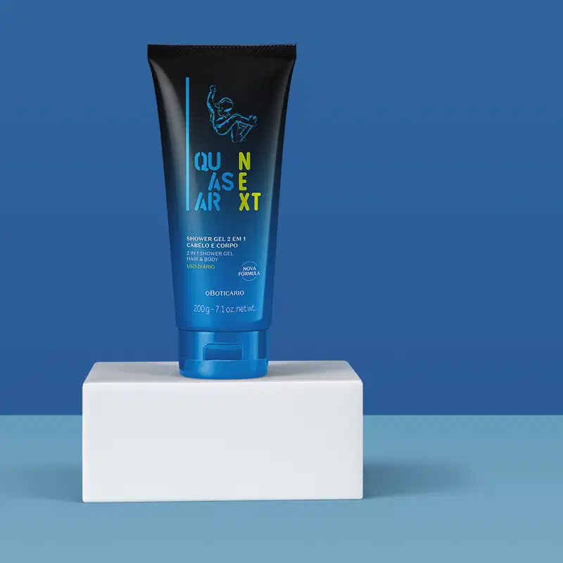 Frasco degradê de azul com preto de gel de banho para corpo e cabelo 2 em 1 da marca Quasar Next, com ilustração de skatista azul sobre plataforma quadrada branca sobre fundo azul.