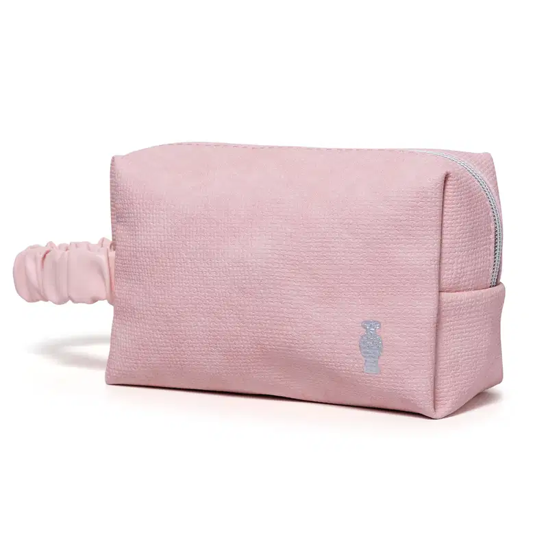 Nécessaire retangular de tecido na cor rosa com alça de transporte franzida e logo da marca O Boticário estampado.