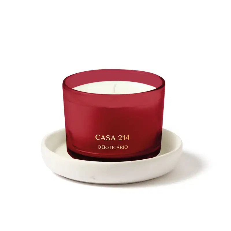 Vela perfumada branca em recipiente vermelho acompanhada de um suporte para velas branco, ambos da marca Casa 214.