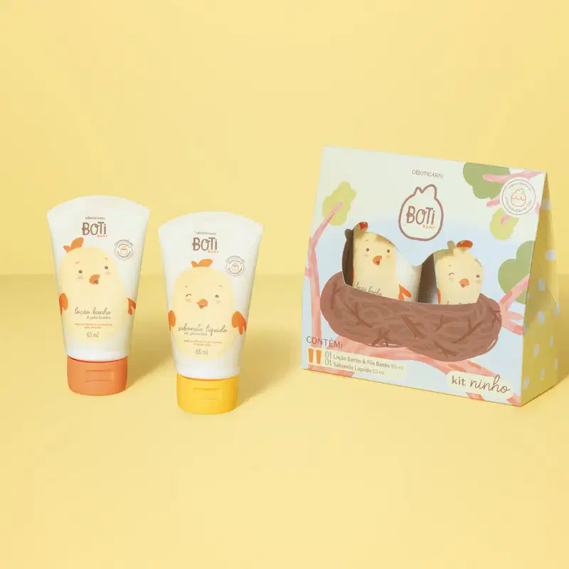 Duas bisnagas brancas com tampas laranjas e desenhos de pintinhos amarelos com detalhes laranjas, sendo de loção banho e pós banho e de sabonete líquido. Ao lado dos produtos, a caixa com desenho de pintinhos no ninho. Tudo está em fundo laranja.