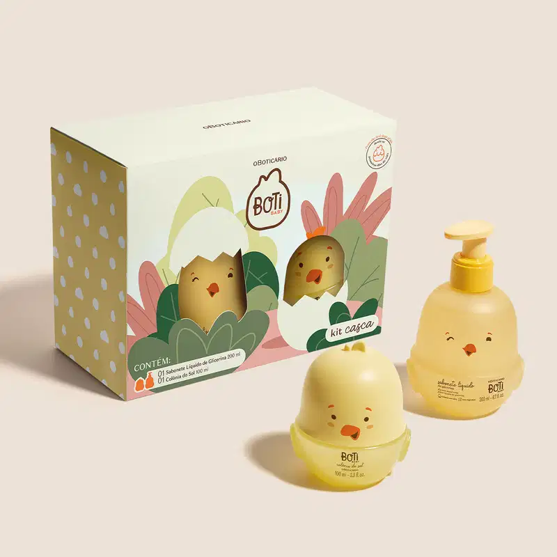 Kit Boti Baby que traz uma embalagem com desenhos de pintinhos saindo de dentro da casca do ovo em meio a folhagens.  Ao lado da embalagens, dois frascos em forma de pintinhos amarelos, sendo um de sabonete líquido de glicerina e outro de colônia do sol.