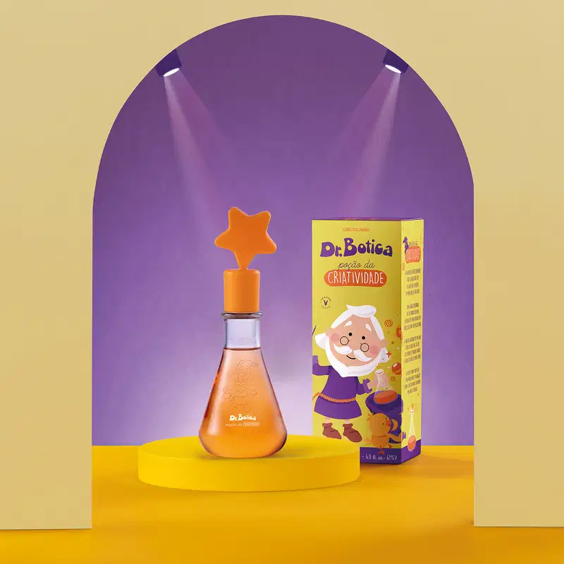 Frasco com líquido laranja e tampa com estrela na ponta também laranja contendo 120ml de colônia infantil Poção da Criatividade Dr. Botica em destaque sobre superfície amarela, com iluminação roxa ao fundo.
