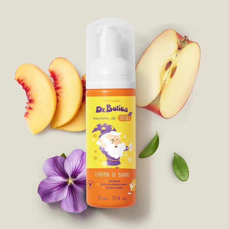 Espuma de banho corporal Nuvem de Ideias Dr. Botica em frasco com tampa branca e rótulo amarelo e laranja com ilustração do personagem da marca sobre superfície clara, com fatias de pêssego, maçã e flor roxa ao redor, em cenário minimalista e natural.