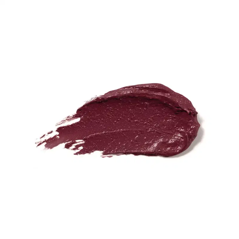 Textura cremosa e brilhante do batom glossy na cor Vinho Blackbarry da marca Make B. A aparência é brilhante e leve e está espalhada em superfície branca.