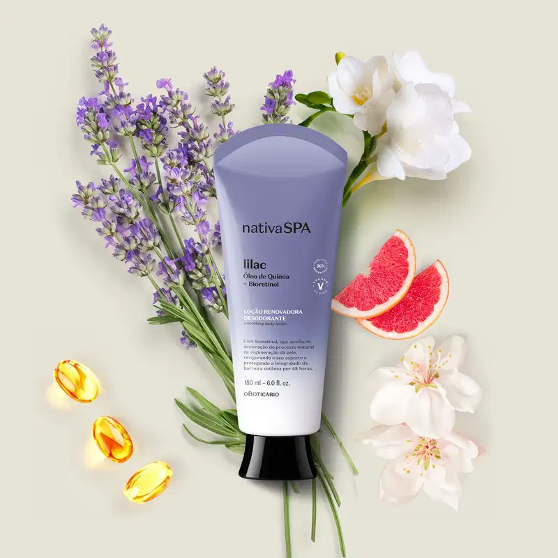 Bisnaga em degradê de lilás e branco com tampa preta e letras brancas e pretas de loção renovadora hidratante corporal Nativa SPA Lilac cercado por flores de lavanda, rosas brancas e fatias de toranja vermelha sobre fundo bege claro.