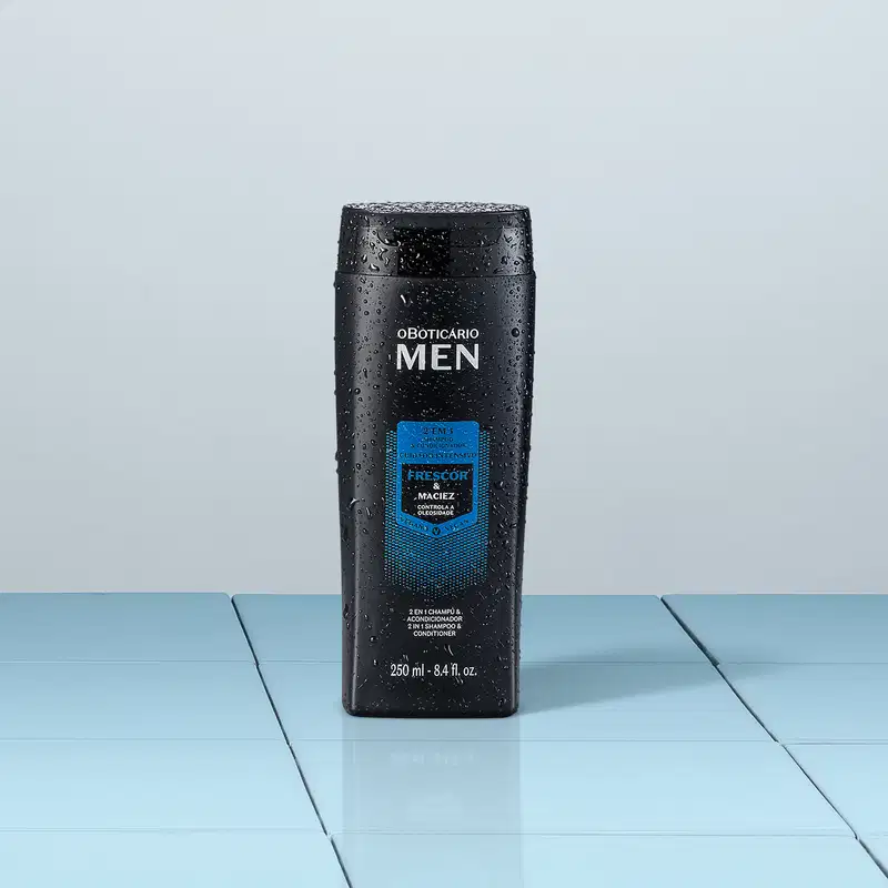 Frasco preto com detalhes azuis e letras brancas contendo 250ml de shampoo e condicionador 2 em 1 da marca Men em fundo cinza e superfície da mesma cor simulando tábuas.