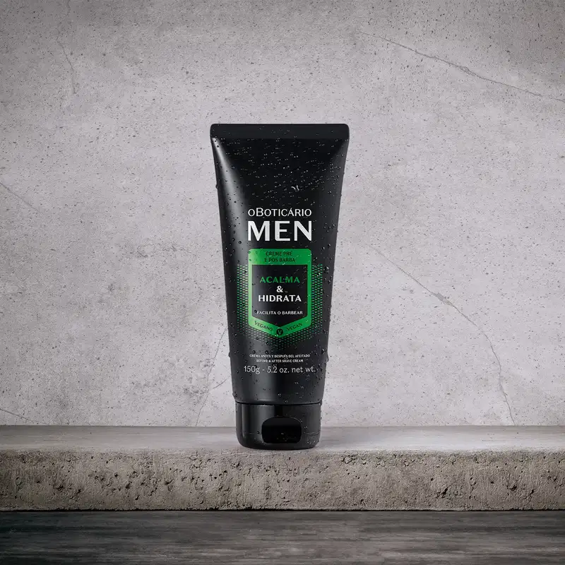 Frasco preto com detalhe verde e letras brancas de creme pré e pós barba da marca Men, sobre superfície cinza com textura granulada, em ambiente minimalista e monocromático.