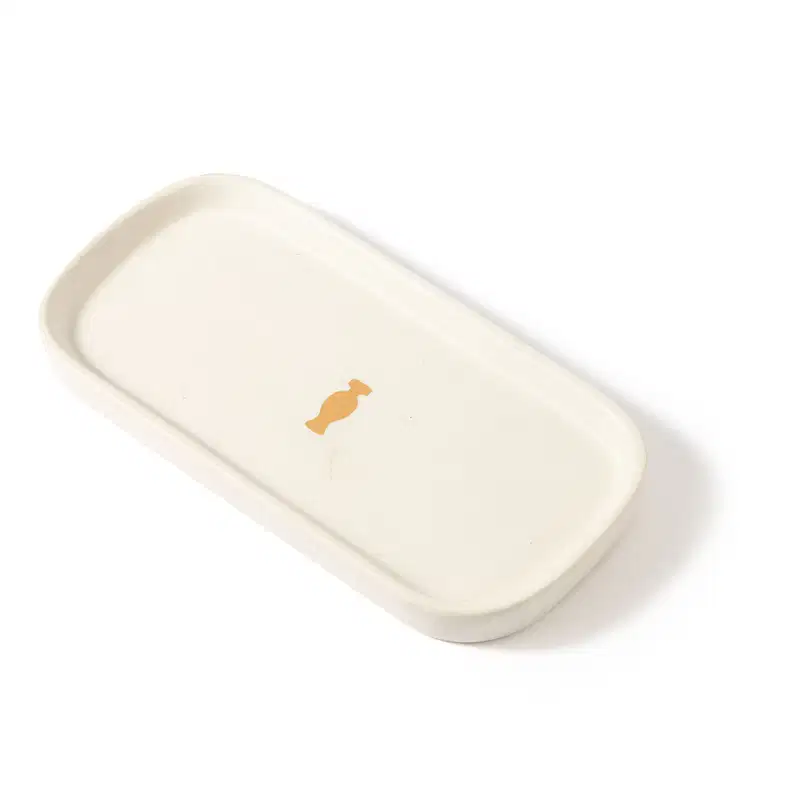 Bandeja para lavabo branca da marca Casa 214 no formato retangular com cantos arredondados e com logo do Boticário em dourado no centro.