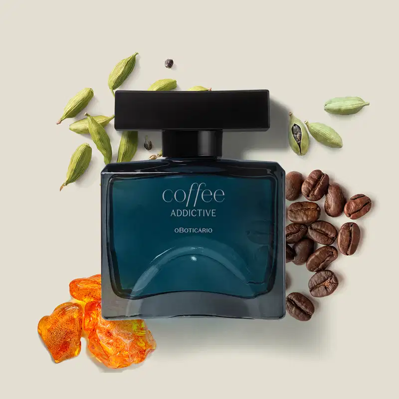 Vidro quadrado azul com tampa retangular preta e rótulo com letras cinzas contendo 100ml de desodorante colônia Coffee Addictive Oriental Aromático sobre superfície clara, com grãos de café e flores ao redor, em ambiente minimalista e neutro.