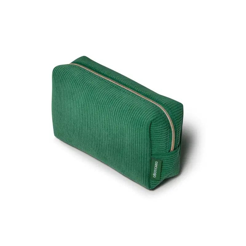 O produto apresentado é uma necessaire de cor verde, com um design de linhas retas e textura canelada com zíper dourado que percorre toda a extensão da peça, permitindo acesso ao seu interior. O logo da marca "O Boticário" é visível na parte frontal