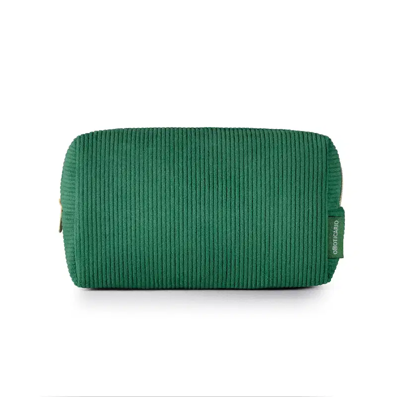 O produto apresentado é uma necessaire de cor verde escuro, com textura canelada. Possui um zíper na parte superior e uma etiqueta com o logotipo da marca O Boticário visível.
