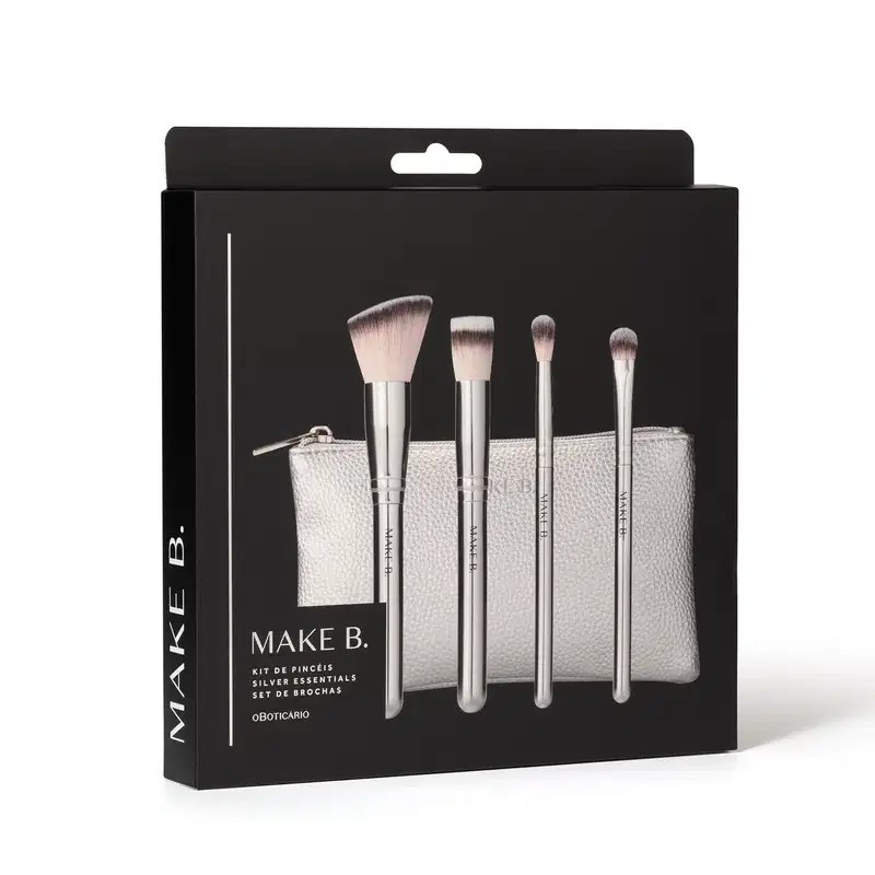 Kit de pincéis de maquiagem Make B. Silver Essentials em embalagem preta contendo um estojo prateado e quatro pincéis com cabos prateados e ponta de cerdas bicolores e macias. O nome da marca está gravada em todos os itens.