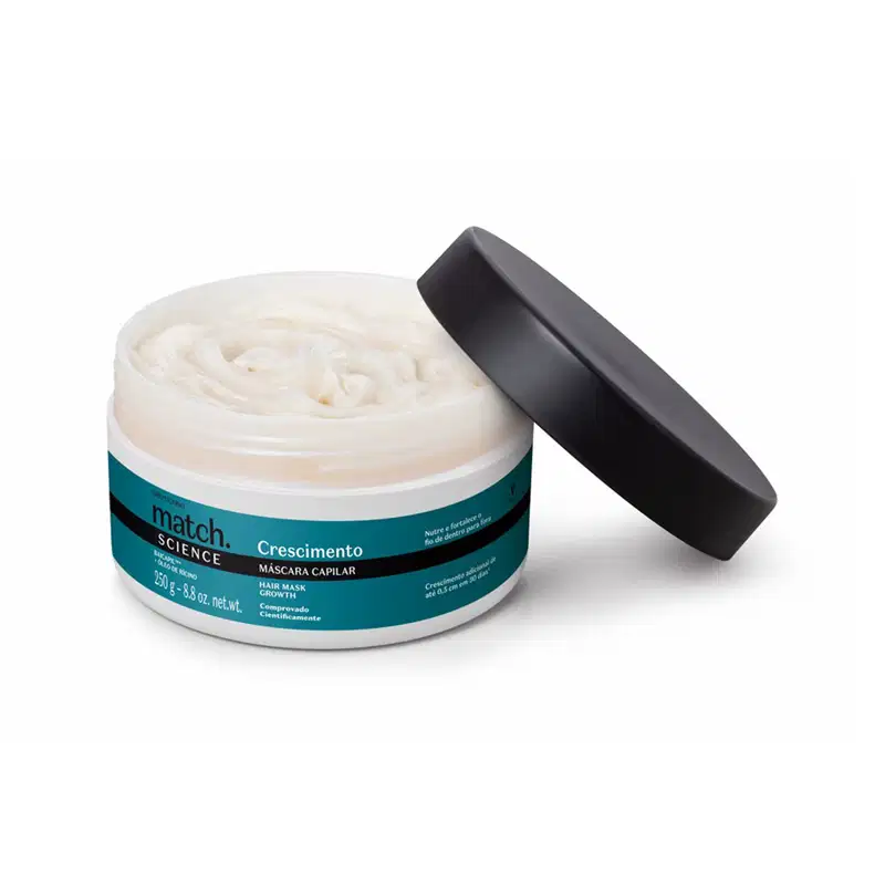 Pote branco aberto com creme branco dentro dele e tampa preta apoiada na embalagem. O produto possui rótulo na cor azul metalizado, preto e branco.