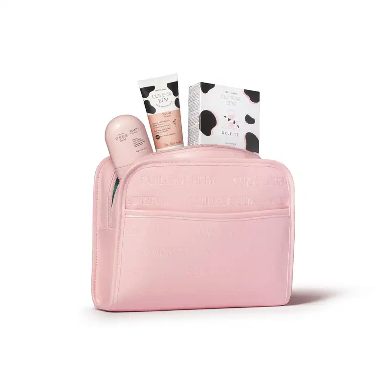 Necessaire em material sintético na cor rosa claro com zíper. Possui formato retangular com cantos arredondados. O estojo apresenta textura fosca e, de dentro dele, estão saindo vários produtos da marca Cuide-se Bem.