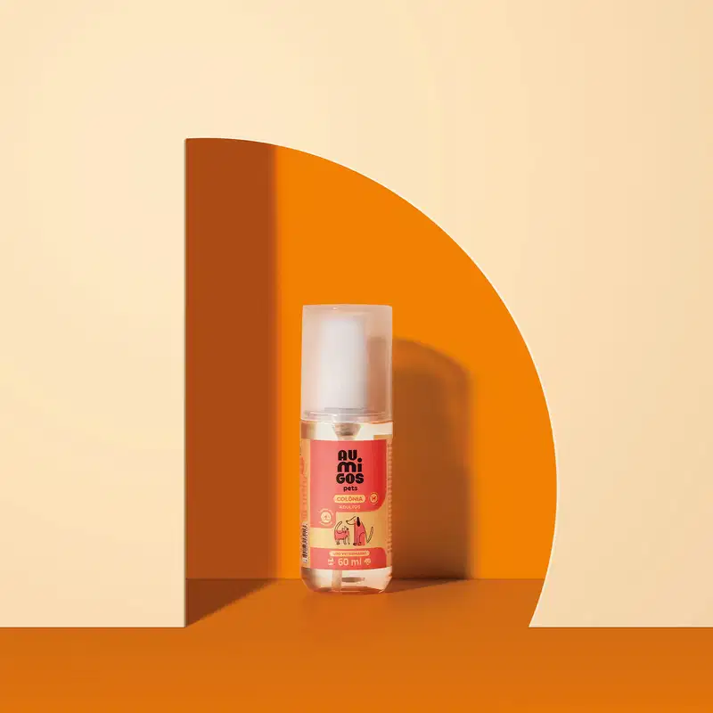 Um frasco de colônia adultos da marca Au.Migos Pets está em um arco laranja com fundo e superfície na mesma cor.