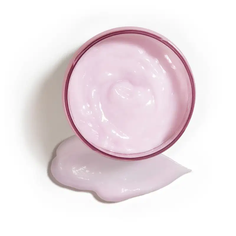 Potede creme hidratante corporal Liz Flora aberto, mostrando o creme branco dentro do recipiente e um pouco do produto espalhado na superfície branca.