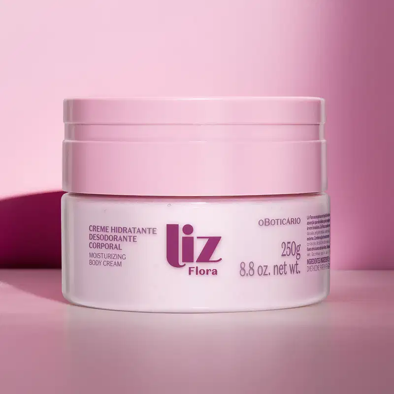 Pote rosa claro com tampa rosa e letras vinho contendo 250g de creme hidratante corporal Liz Flora em fundo rosa com sombras.