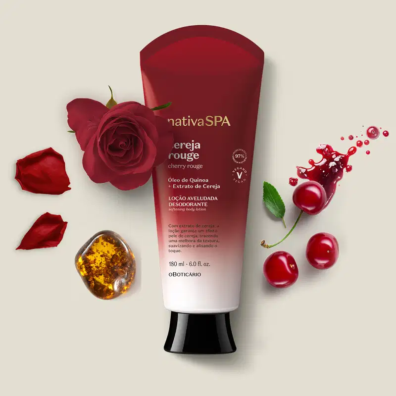 Bisnaga vermelha e branca da marca Nativa SPA Cereja Rouge com rosa vermelha, pétalas e respingos de líquido vermelho em superfície clara, com outros elementos decorativos ao redor.
