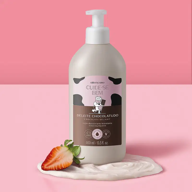 Frasco de loção hidratante Cuide-se Bem Deleite Chocolatudo acompanhada de um creme branco uma morango ao lado, sobre fundo rosa.