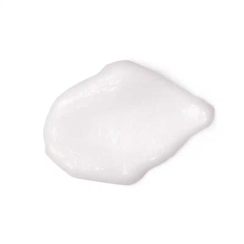 Textura branca, brilhante e densa de um item de cuidados com a pele cobrindo boa parte da superfície, também branca.