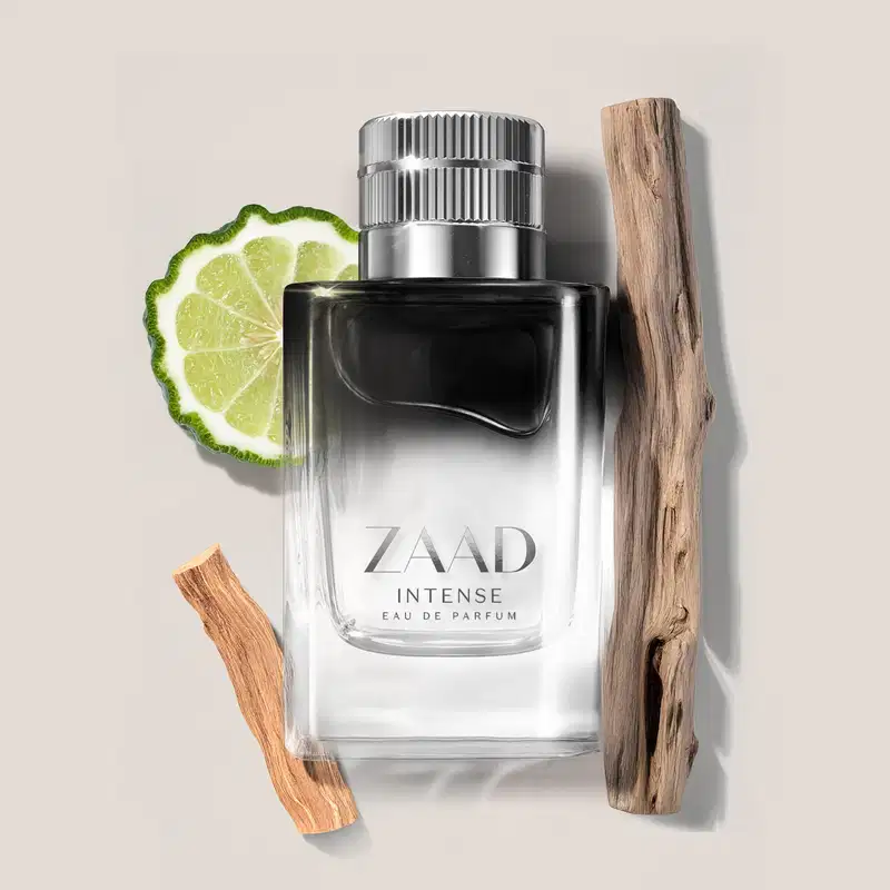 Imagem de um vidro de Eau de Parfum Zaad Intense em preto e prata com limão e madeira ao redor, em fundo cinza.